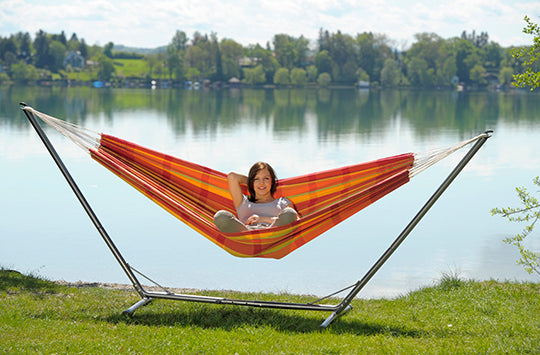 A woman sat by the lake in her brightly coloured barbados papaya hammock and metal stand.