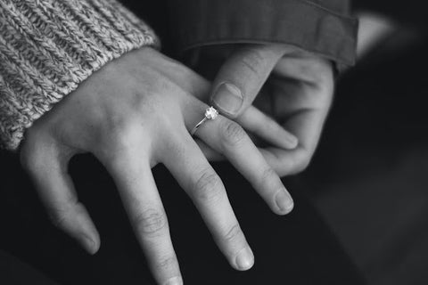 Woman wearing engagement ring with man holding hand