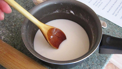 Mixing cornflour and milk in a pan with a wooden spoon