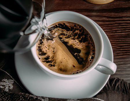 Mixing Rage coffee instant coffee with hot water in a cup