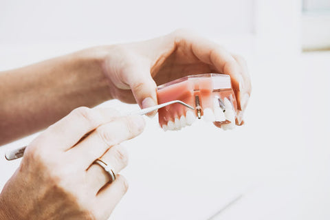 Person picking dentures with gum pick, for AutoBrush blog