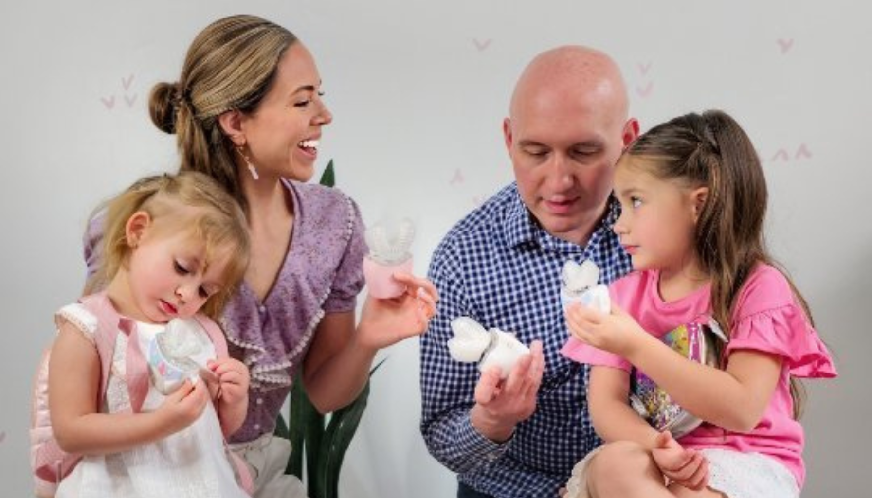 Family of four examining dental models with interest and smiles.