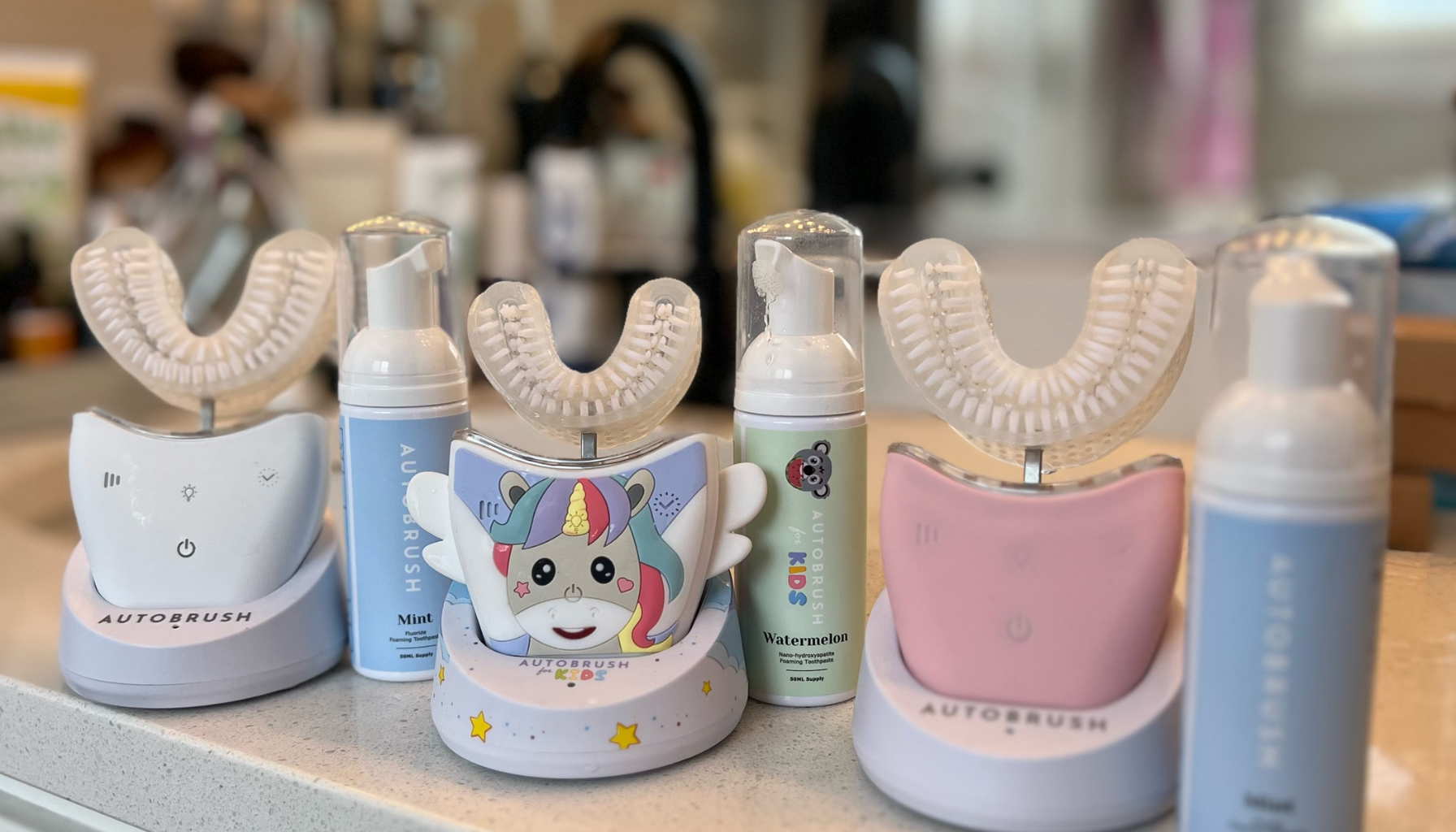 Three automatic toothbrushes with foam dispensers on a bathroom counter.