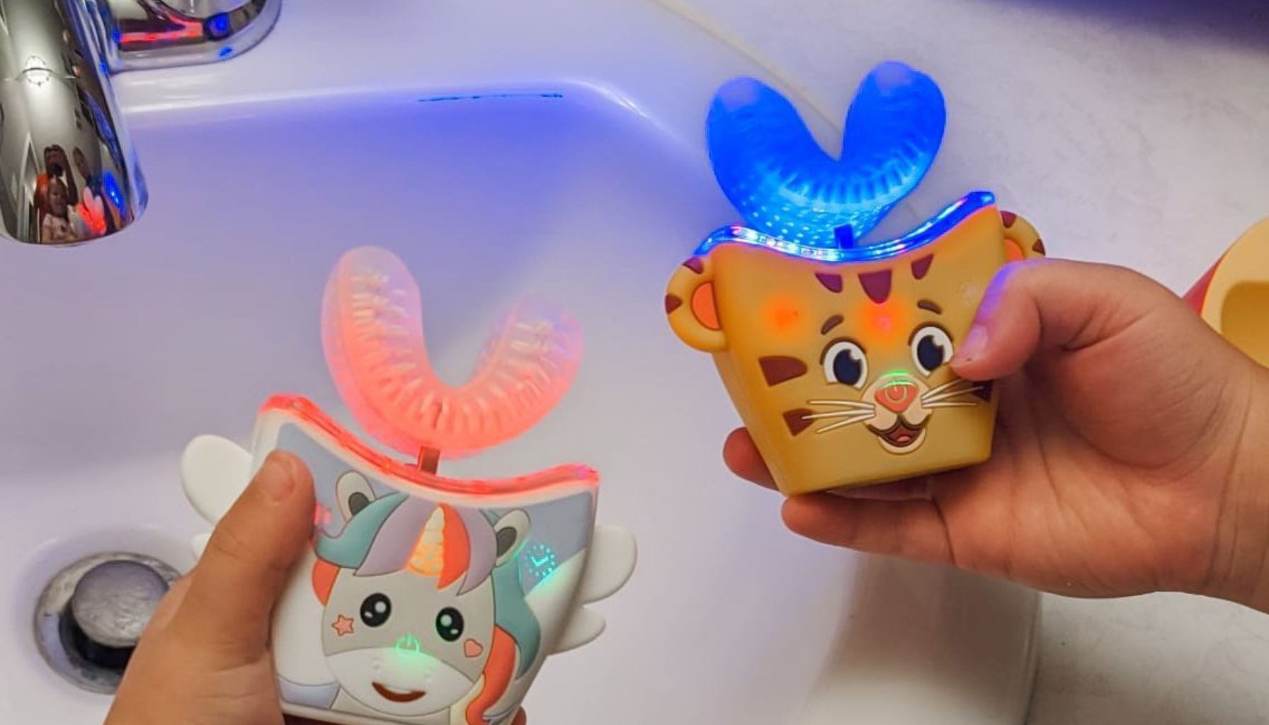 Hands holding illuminated animal-themed dental hygiene timers for children by a sink.