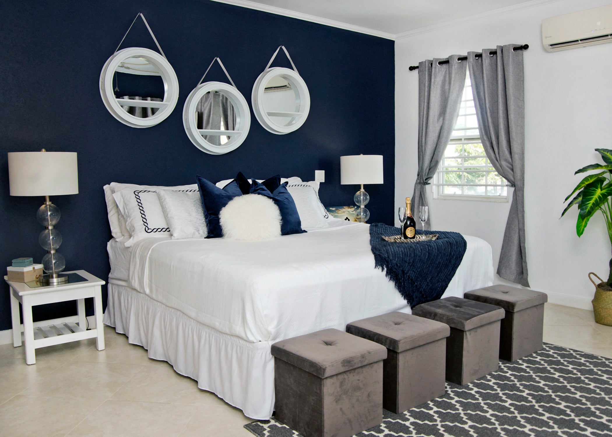 Bedroom with navy accent wall, and neutral decor. Clam, sophisticated, and elegant design by a Harris Paints' Colourcentre staff member