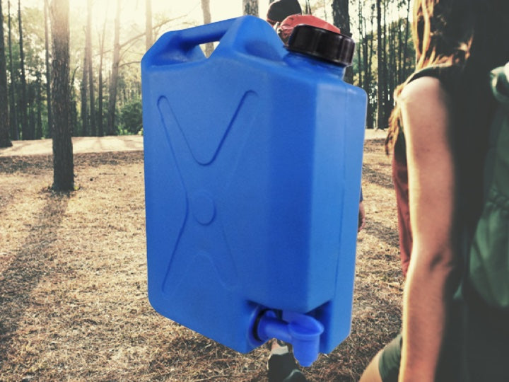 Couple hiking in the woods with a blue Pionee rplastcis water tank in the foreground
