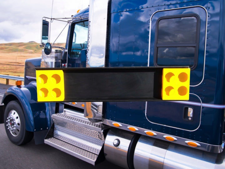 Blue truck driving with a yellow and black Pioneer plastics chevron board in the foreground