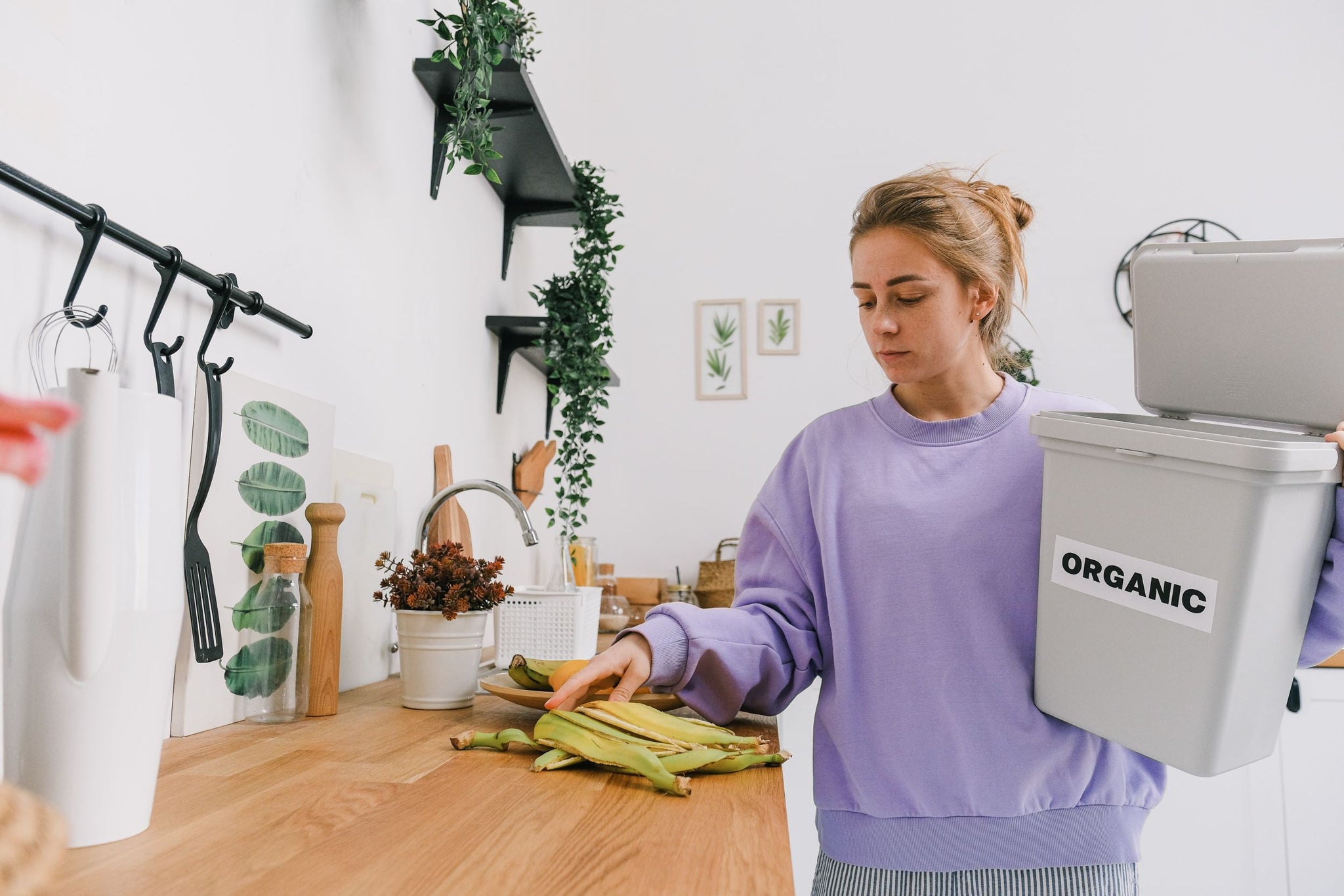 Woman discarding banana peel into organic waste bin