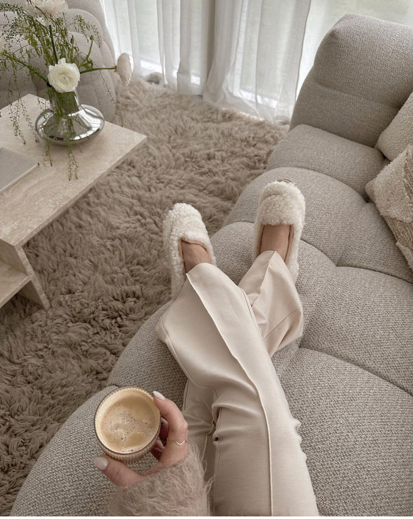 Woman holding a coffee cup on a beige sofa