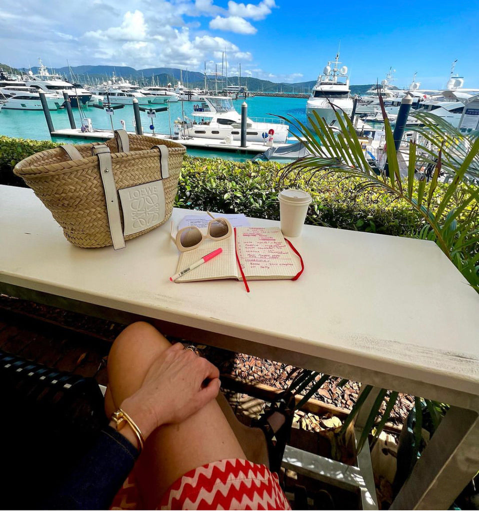 Woman at cafe with notepad in front of a sunny marina