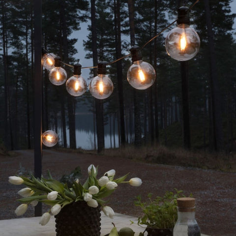 Festoon lighting hung above an outdoor table