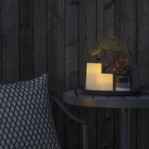 A table adorned with outdoor LED candles and a plant