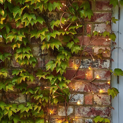 solar ivy lights glowing on a brick wall