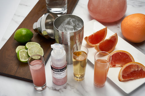 cocktail bartending tools with citrus garnish and edible glitter