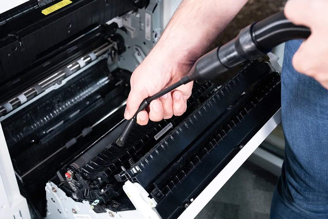 MetroVac Cordless DataVac detail brush attachment removing dust from a server’s front panel in a tech environment.