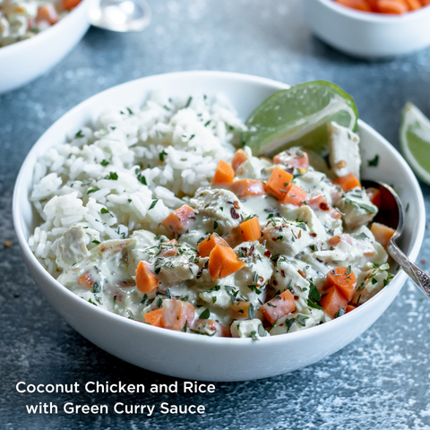 Coconut Chicken and Rice with Green Curry Sauce. White bowl contains chicken, diced carrots, and seasonings atop a bed of white rice. Garnished with a lime wedge.