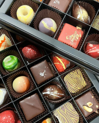 "A beautifully presented box of handcrafted chocolates, featuring an assortment of decadent flavors and intricate designs."