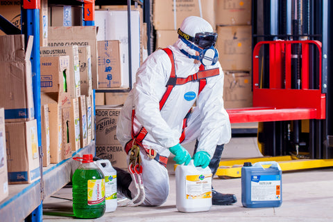 Persona con traje de materiales peligrosos rodeada de productos químicos