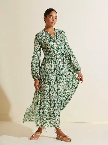 Front-facing woman wearing a long white and green dress.This long dress creates a soft and flowy bohemian silhouette with long puffed sleeves.