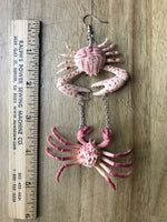 Crab earrings rest next to a ruler.  Th earrings will hanf almost 5 inches long.