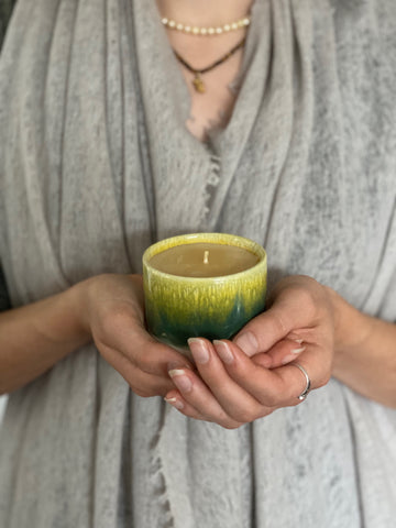 Hands holding sip cup candle green