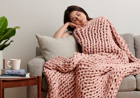 women resting on couch with bearaby blanket