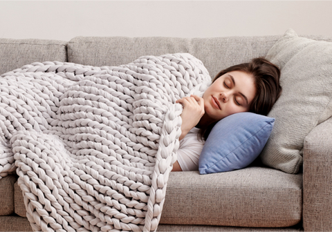 women sleeping on couch with bearaby grey knitted blanket