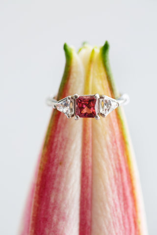 The Pink Princess-Cut Ring with a dark pink Maine tourmaline on a pink and green flower bud