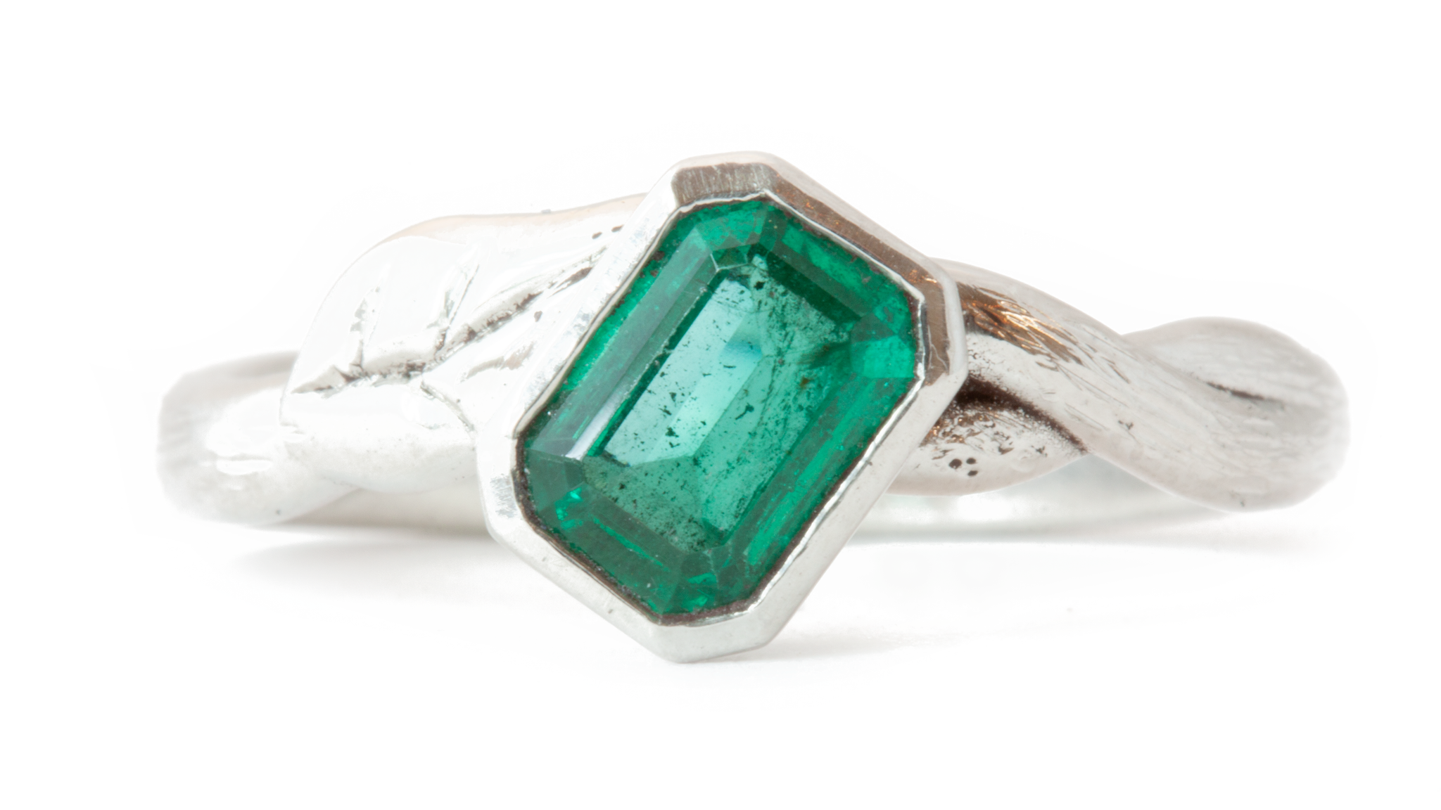 Heirloom emerald in bezel setting on platinum band with birch texture and leaf design