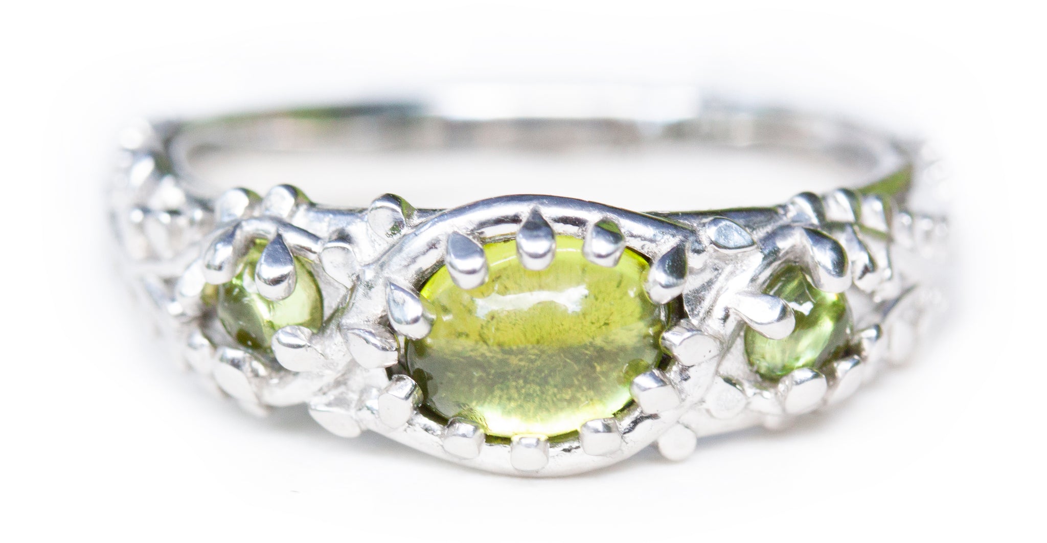 Custom peridot ring with moss details on a white background