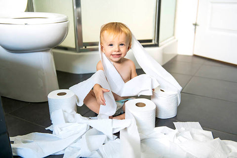 Toddler in the bathroom with toilet paper
