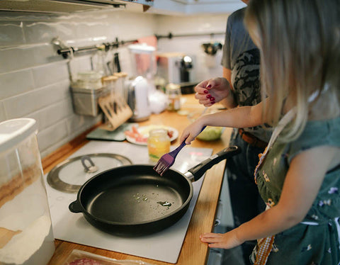 Child helping cook dinner standing on a learning tower