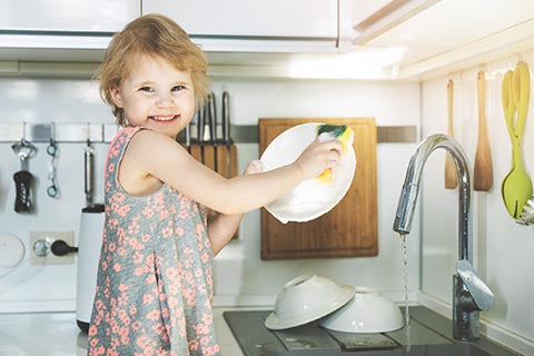 Dish washing concept. Child boy washing the dishes in the kitchen