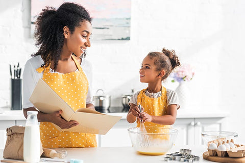 Mother and girl reading a cooking recipe in the kitchen