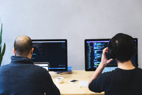 Dos hombres trabajando frente a computadoras: artículo de SideTrak sobre cómo ser más productivo