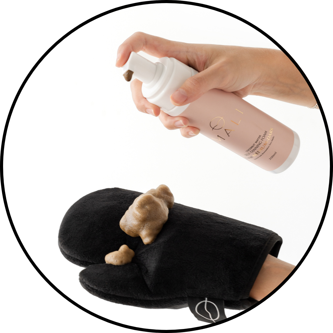 Hand dispensing lotion onto a mitt against a white background.