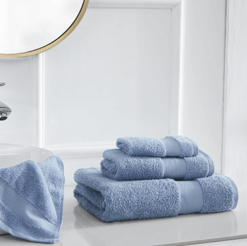 a stack of different sized blue towels from Southshore Fine Linens sitting on a bathroom counter.