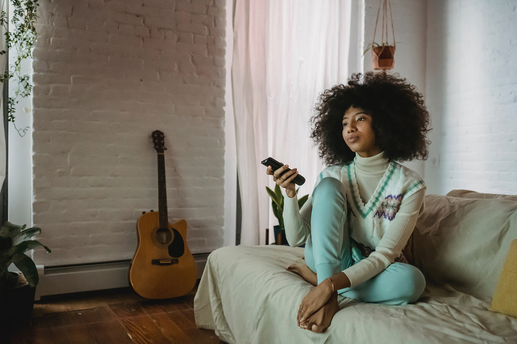 Young woman resting on sofa and watching TV at home