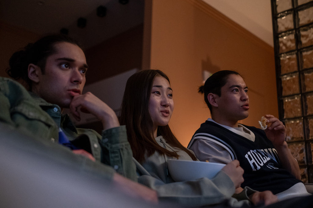 Three friends watching and eating snacks