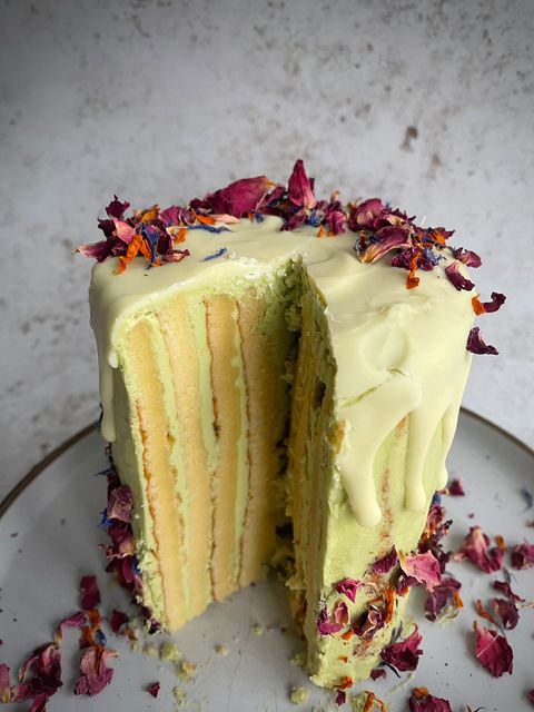 matcha roll cake with a slice removed and edible flowers sprinkled on top