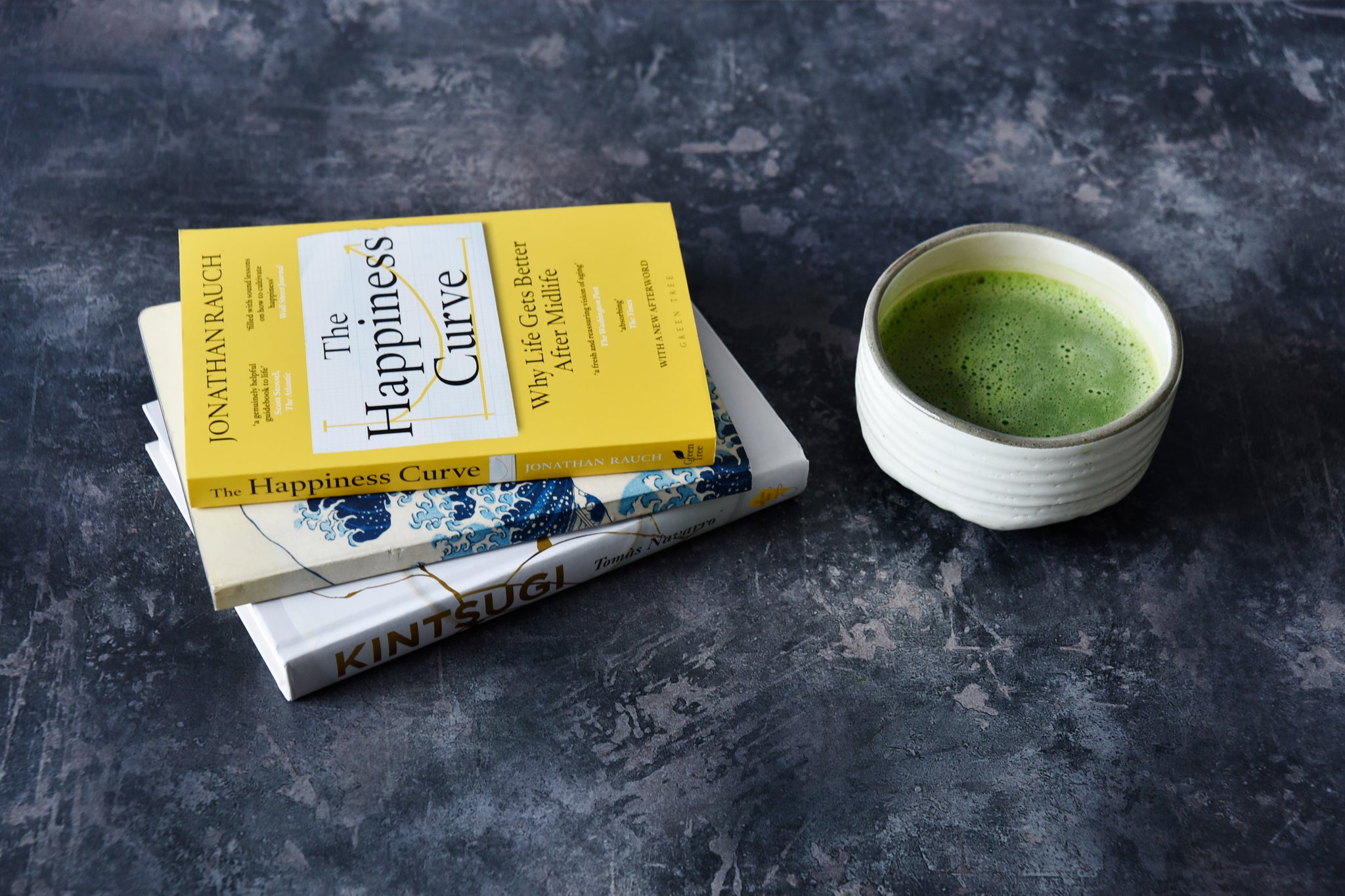 bowl of matcha next to a stack of books