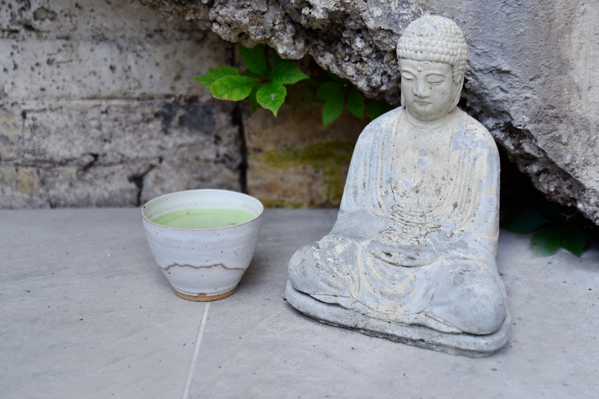 bowl of matcha next to Buddha statue