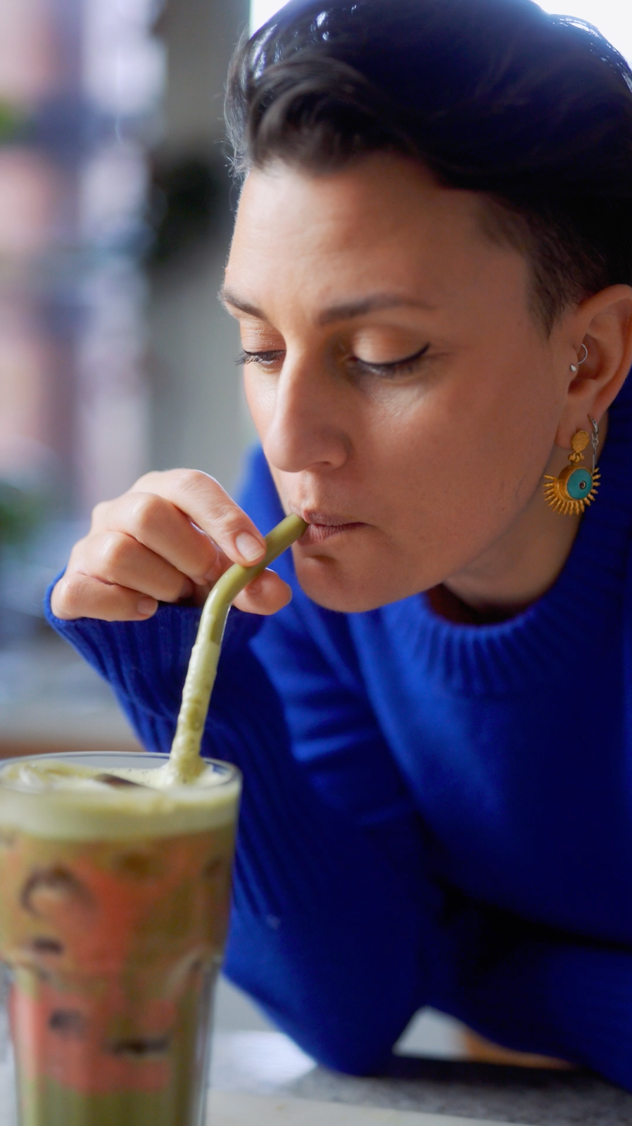 woman drinking matcha and berry smoothie through a straw