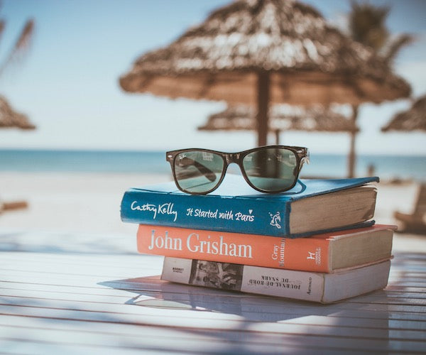 A stack of books and sunglasses on the beach