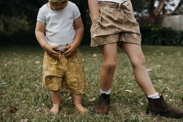 siblings standing next to each other on lawn with indian block printed patterned shorts