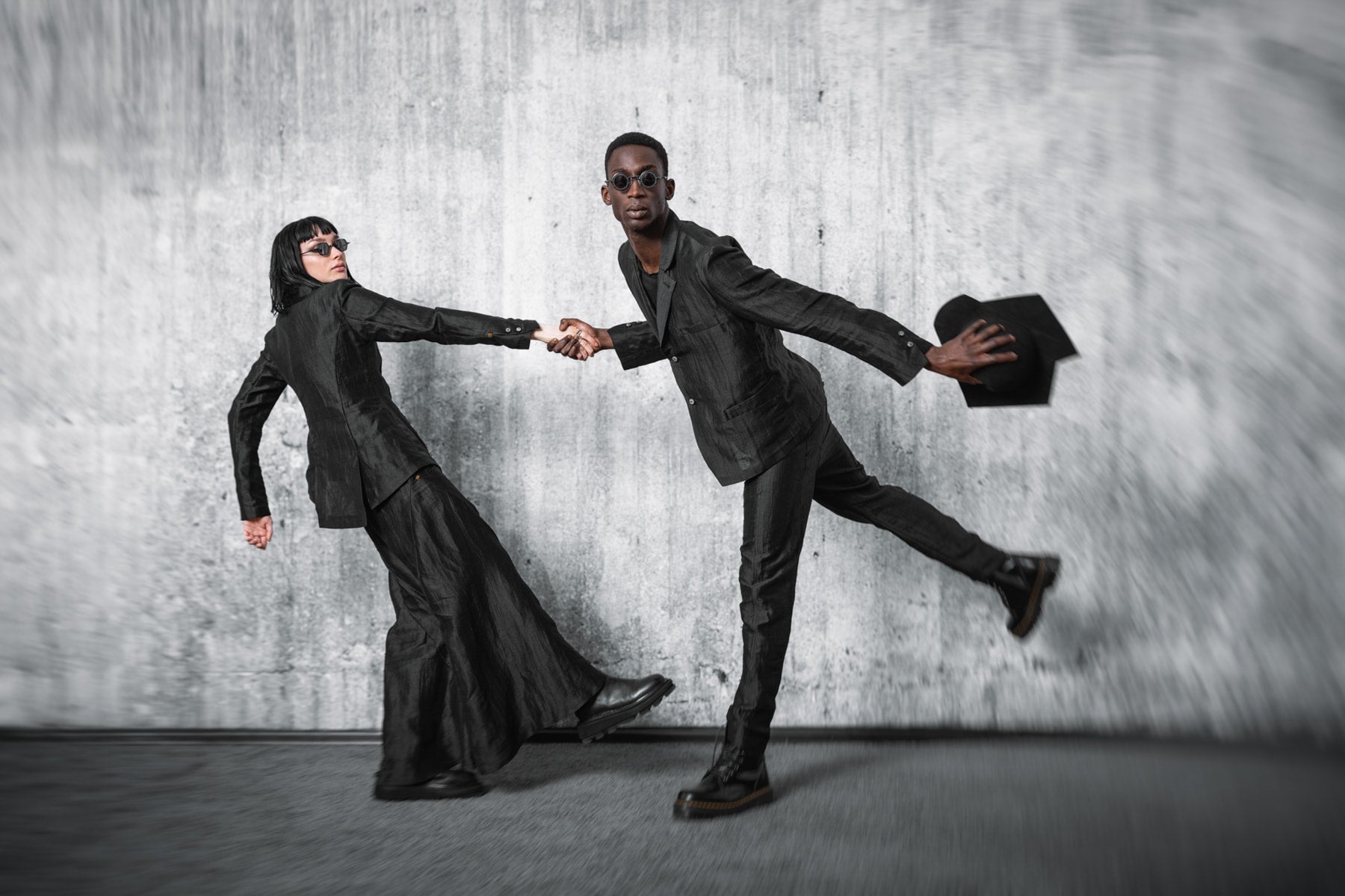 Two people in all-black outfits in the dark avant-garde fashion style of eigensinnig wien