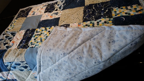 A finished baby quilt, with diagonal lines quilted across it.