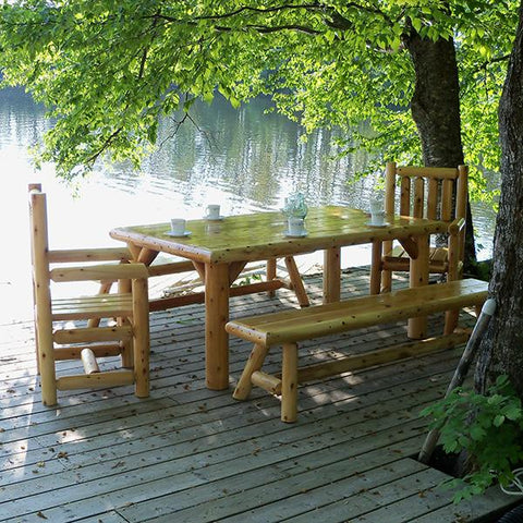 Outdoor dining table and seating close to a lake under a tree