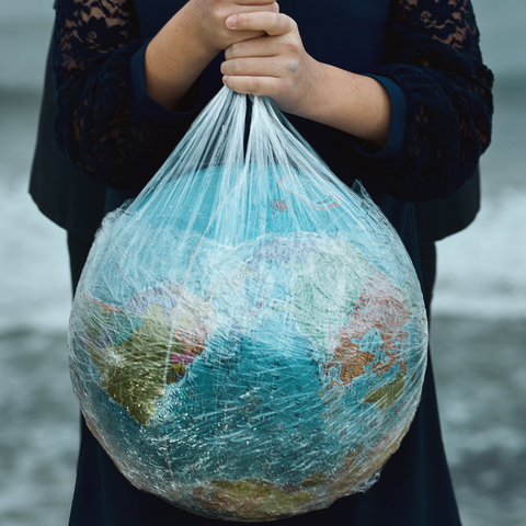 pessoa segurando um saco plastico representando o planeta terra
