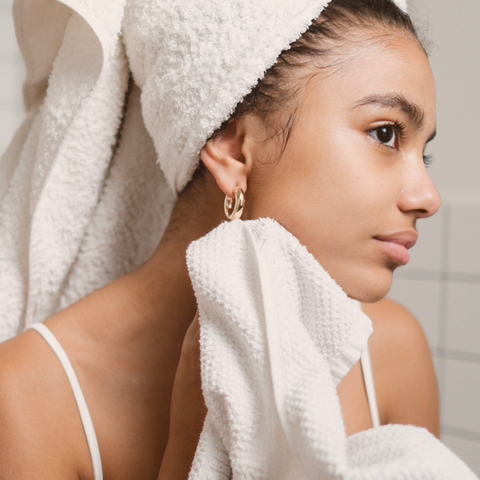 mulher lavando o rosto com a toalha branca na cabeça